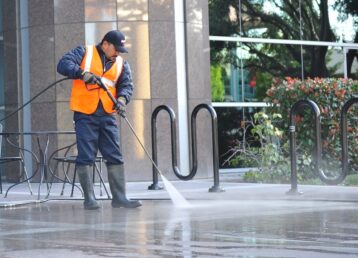 Worker pressure washing concrete